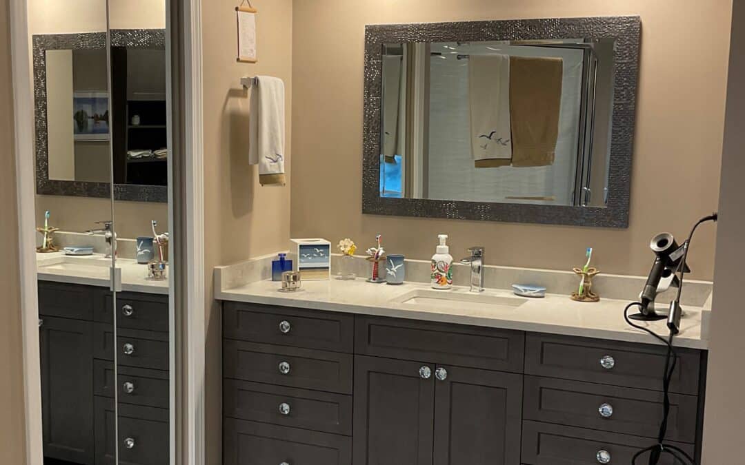 Modern bathroom vanity with dark cabinetry, double sink, decorative mirror, and various toiletries in a Langley townhouse renovation.
