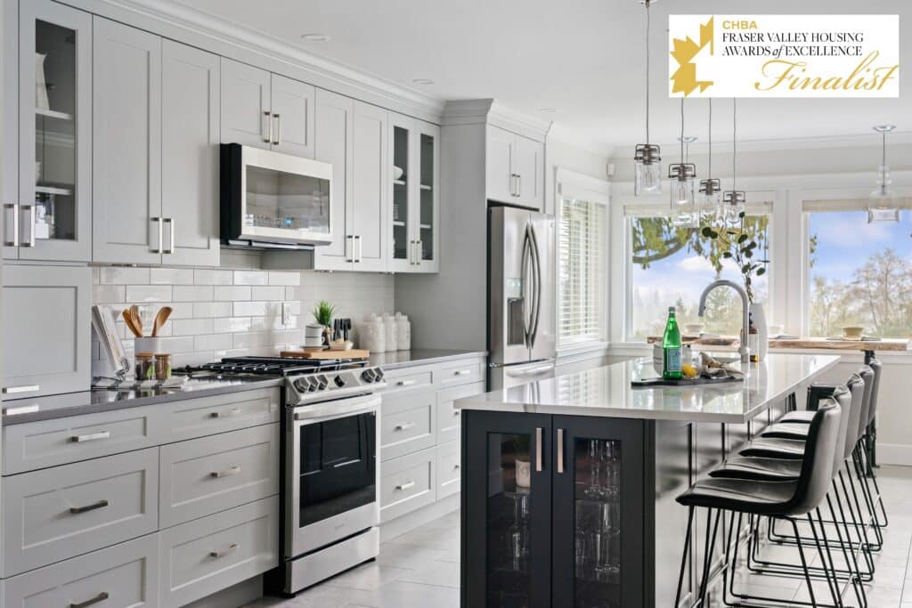 Modern kitchen renovation featuring gray cabinetry, stainless steel appliances, and a sleek island with bar stools, showcasing functionality and contemporary design, recognized as a finalist in the CHBA Fraser Valley Housing Awards of Excellence.